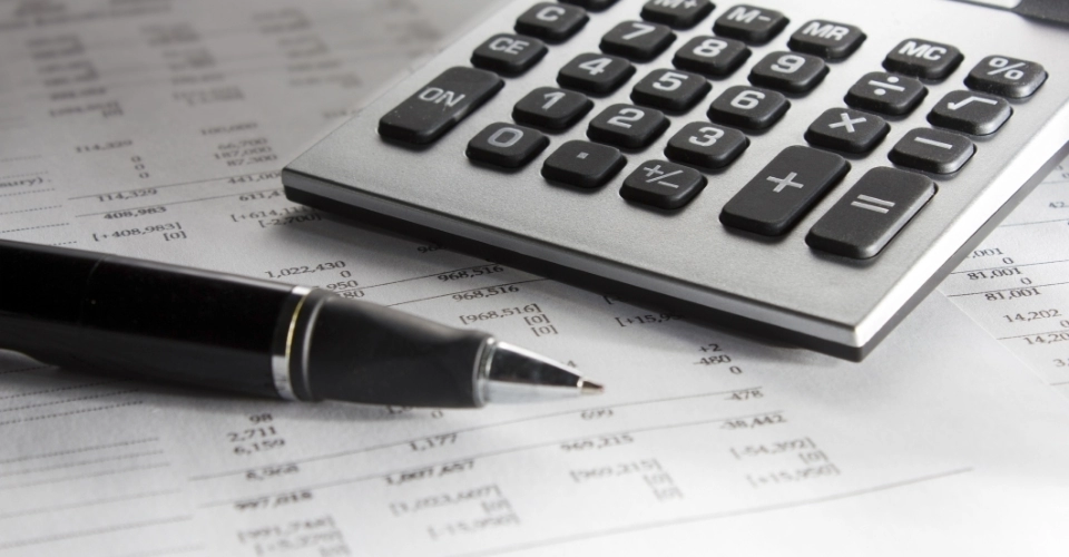 tabela finansowa, kalkulator i długopis